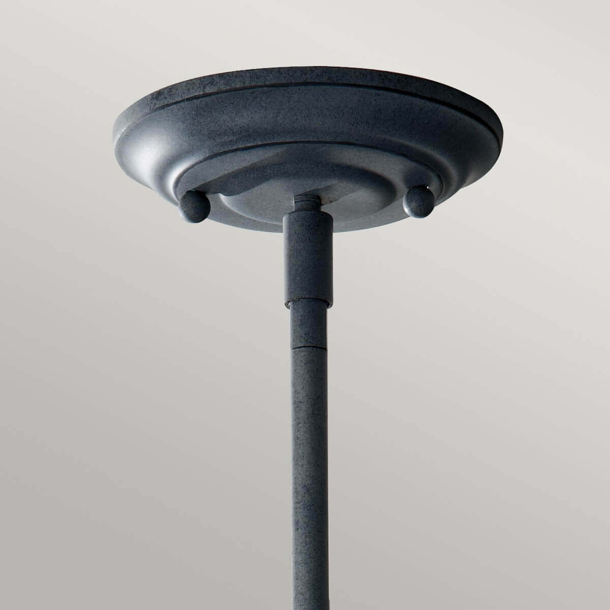 Détail de la rosace métallique patinée fixée au plafond, tige verticale sortante.