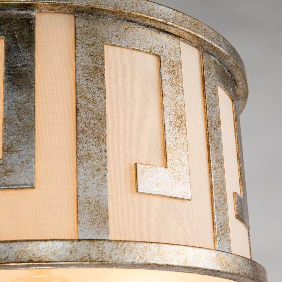 Gros plan sur le motif géométrique ajouré doré devant la toile beige tendue