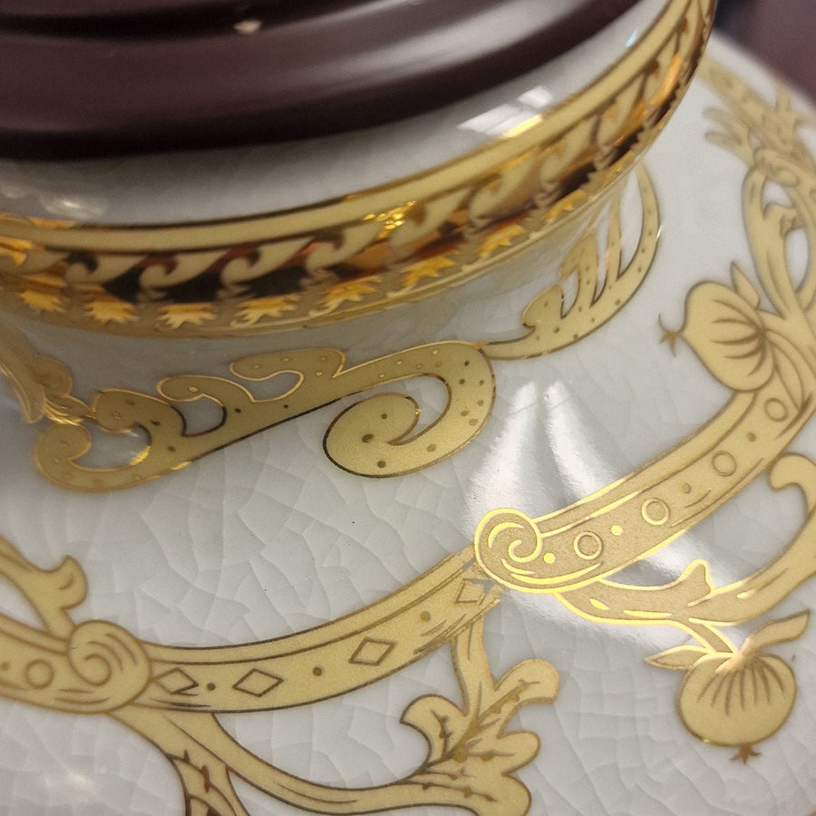 Détail du col doré et du décor de feuillage sur la porcelaine blanche