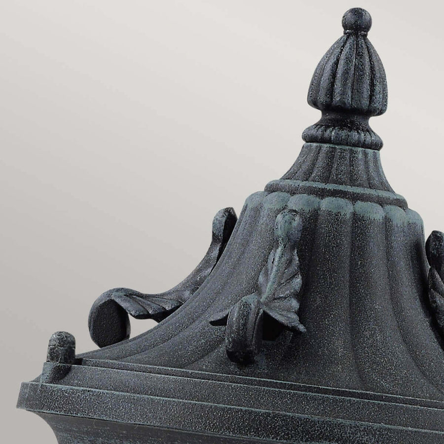 Détail du sommet ornementé avec pompon godronné et volutes en fonte vert patiné