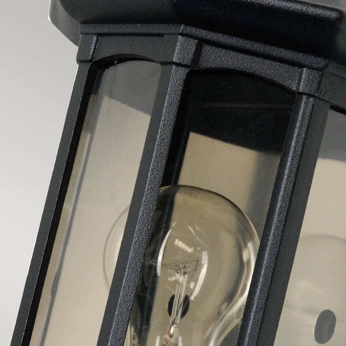 Gros plan sur l'ampoule à filament derrière les vitres du luminaire