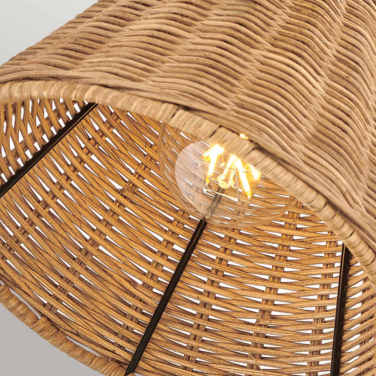 Détail de l'intérieur de l'abat-jour en rotin tressé avec ampoule allumée visible.