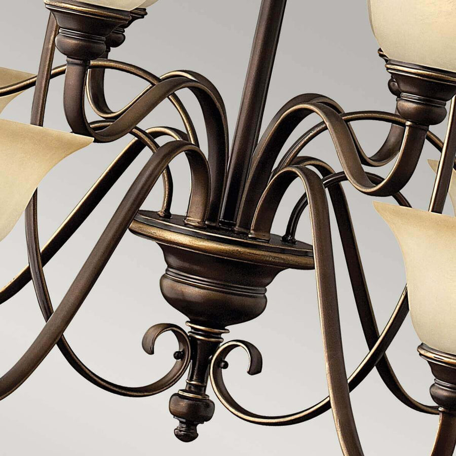 Vue rapprochée du bas du lustre avec ses volutes et sa finition bronze.