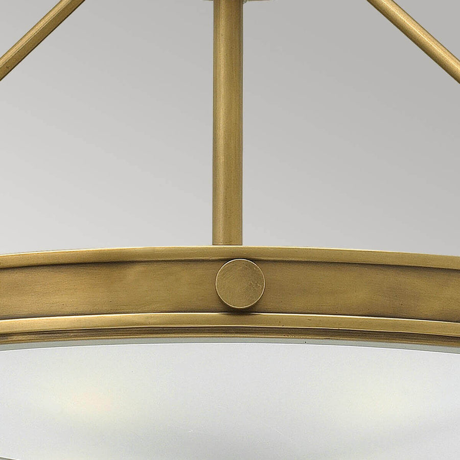 Détail de la tige centrale et du cercle en laiton avec pastille circulaire décorative.