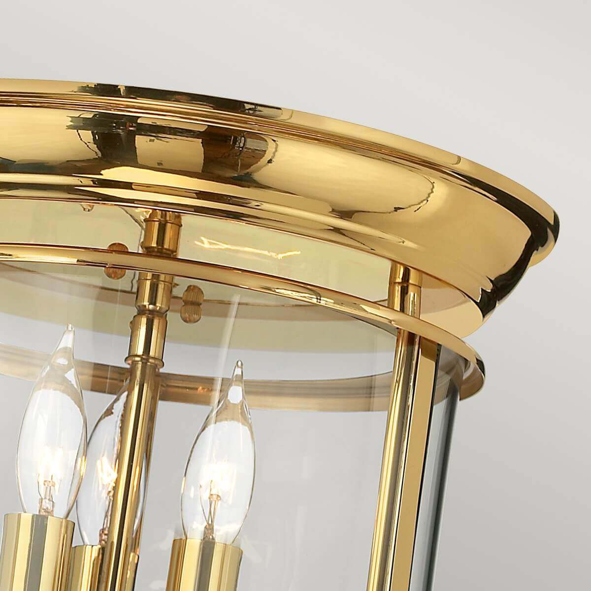 Gros plan sur le haut : cercle en laiton poli, verre transparent et ampoules bougies.