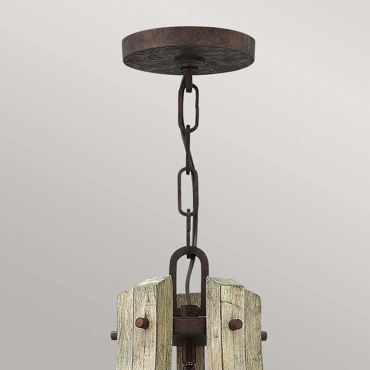 Détail de la fixation au plafond, chaîne et boîtier en métal rouille et bois brut.