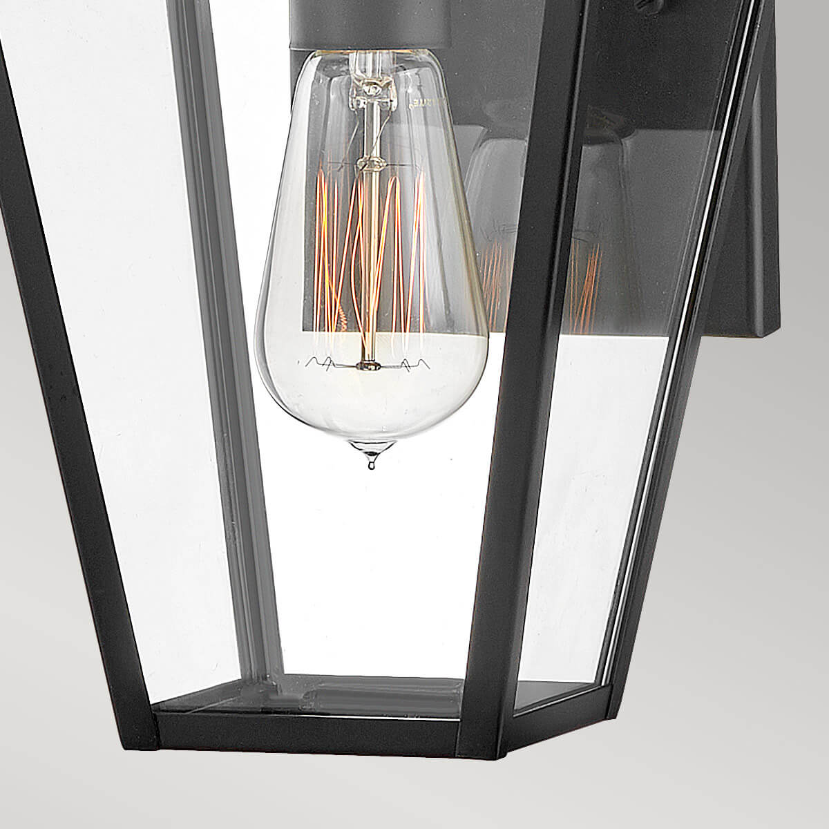Gros plan sur l'ampoule Edison à filament doré derrière le verre transparent
