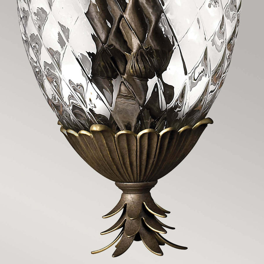 Détail de la base godronnée en bronze et de la pointe feuillue inférieure du luminaire