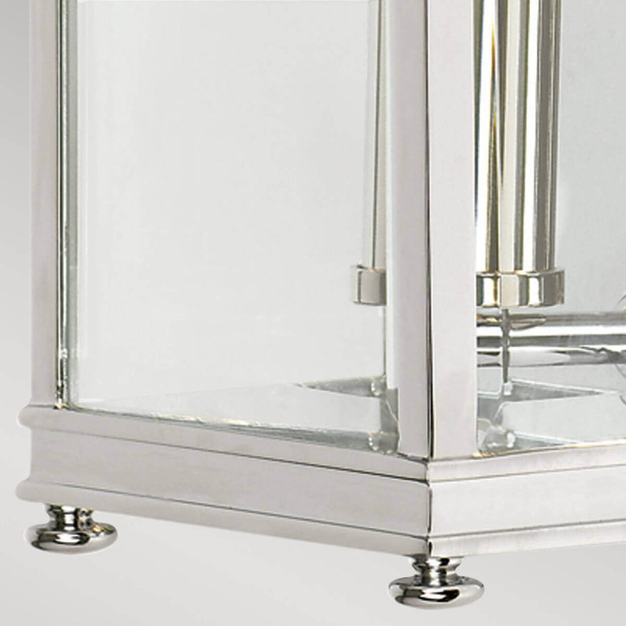 Détail de la base moulurée et des pieds chromés ronds sous le luminaire