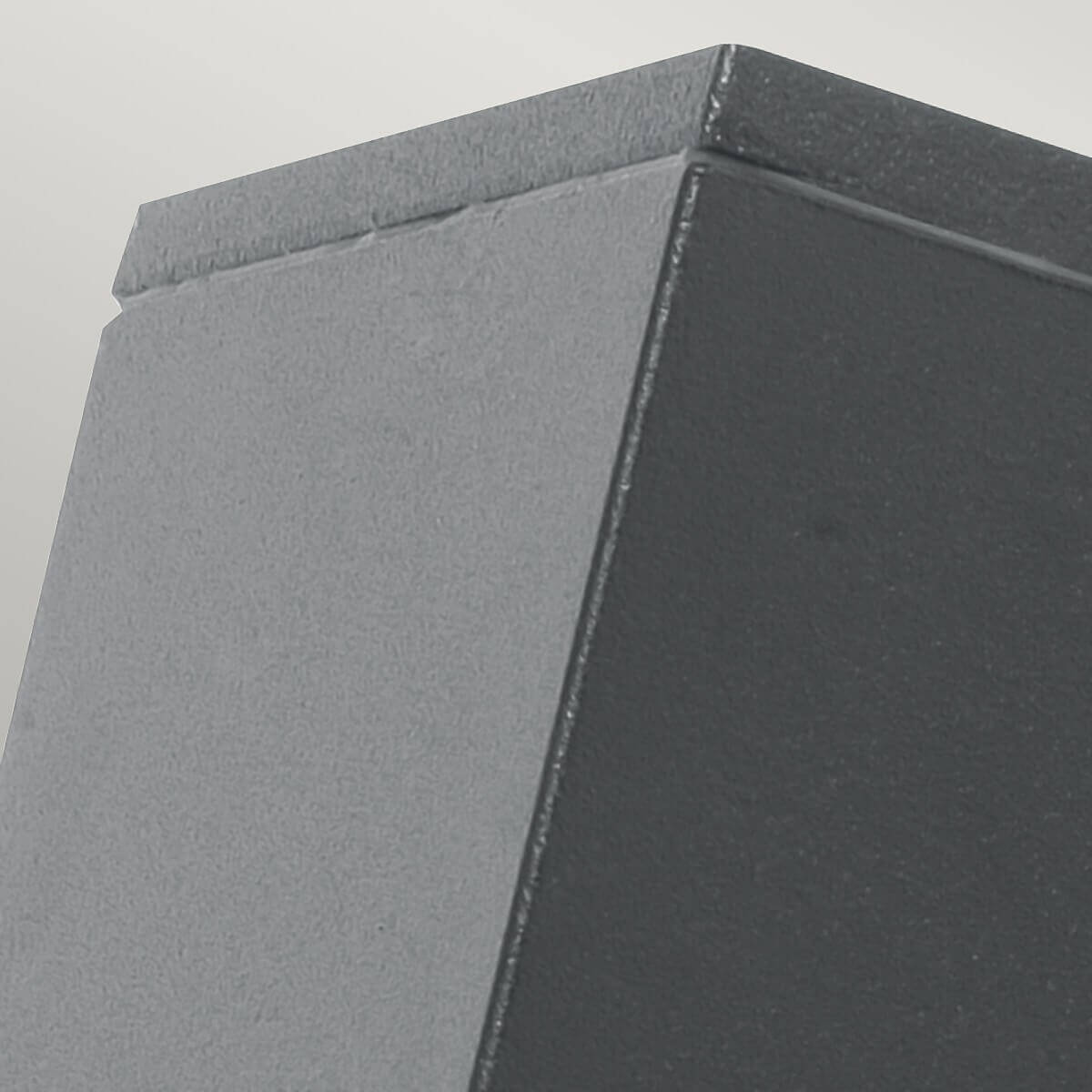 Détail du coin supérieur de l'applique, finition gris foncé texturé et arêtes nettes.