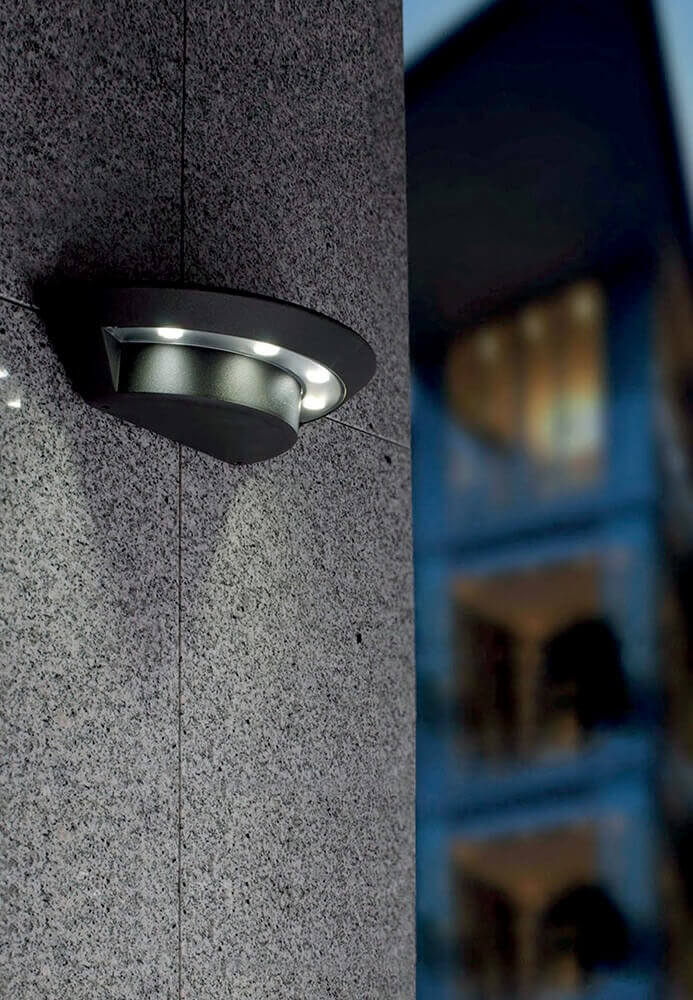 Luminaire installé sur une façade en pierre grise, mise en situation extérieure de jour