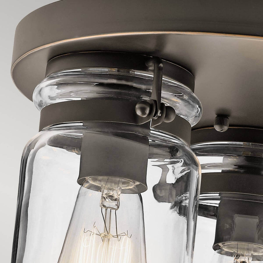 Gros plan sur la fixation du verre et la vis moletée maintenant l'abat-jour au plafonnier
