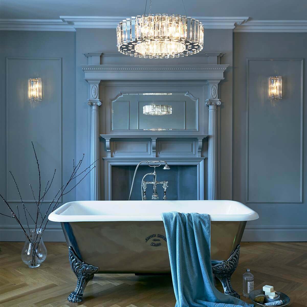 Lustre suspendu au-dessus d'une baignoire îlot dans une salle de bain bleu-gris