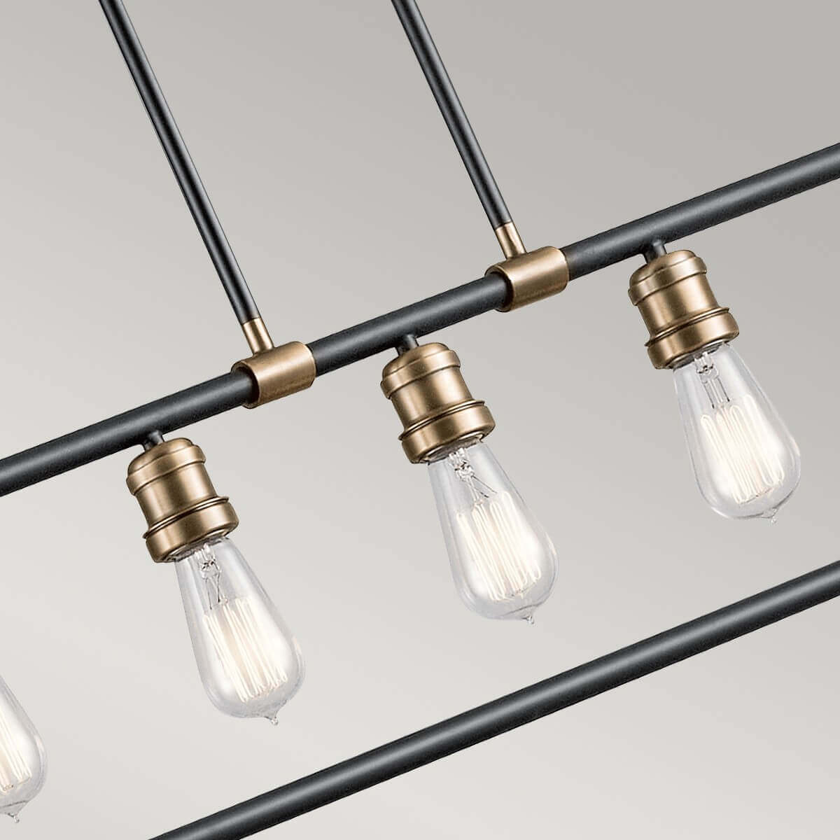 Gros plan sur trois douilles dorées et ampoules Edison fixées sur le cadre tubulaire noir.