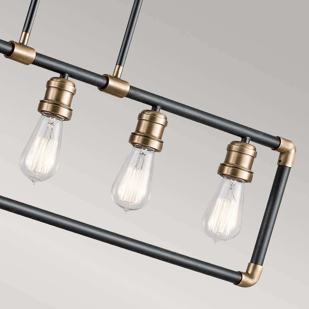 Vue rapprochée des ampoules transparentes et du raccord d'angle en laiton du luminaire.