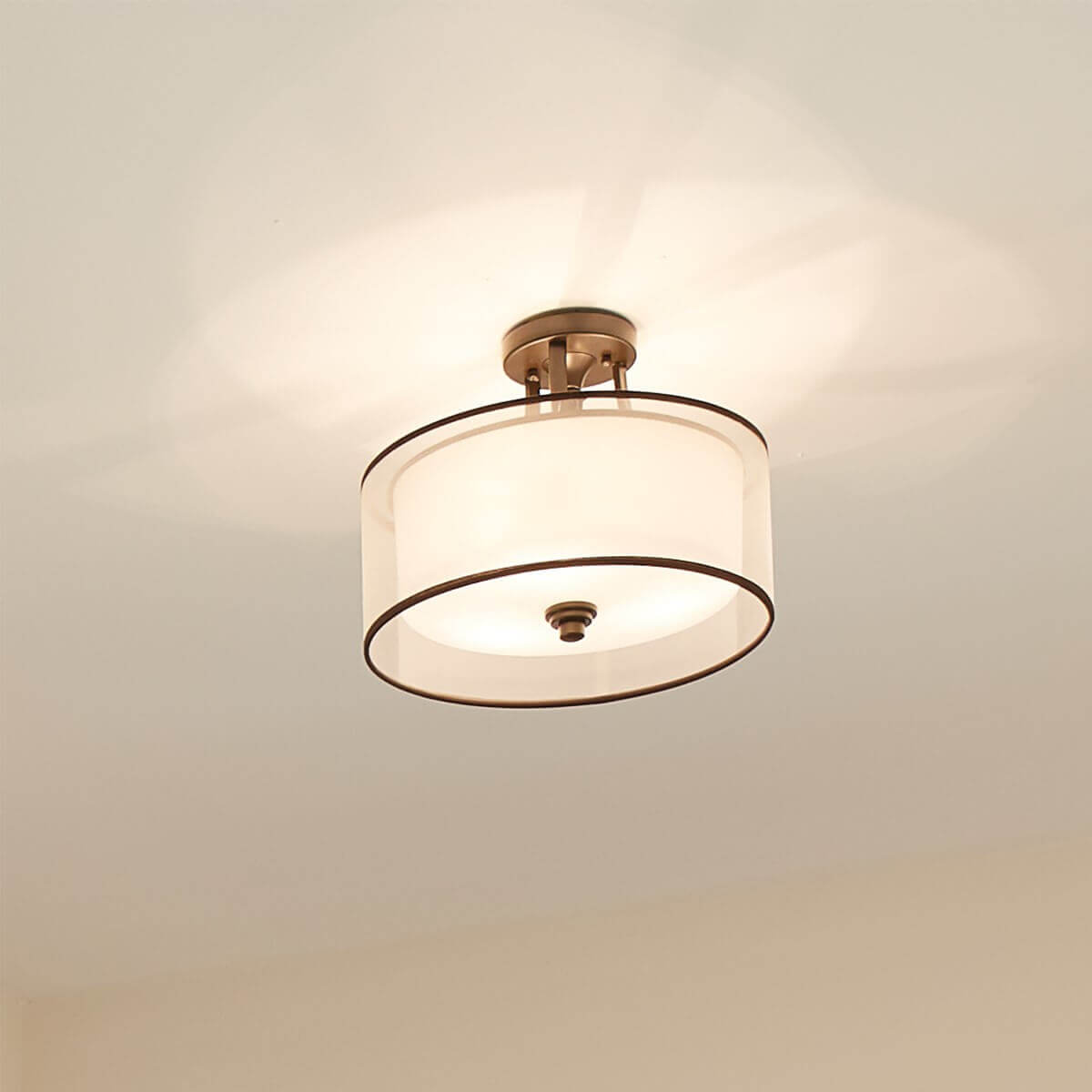 Plafonnier allumé au plafond blanc, halo de lumière chaude diffusée en éventail