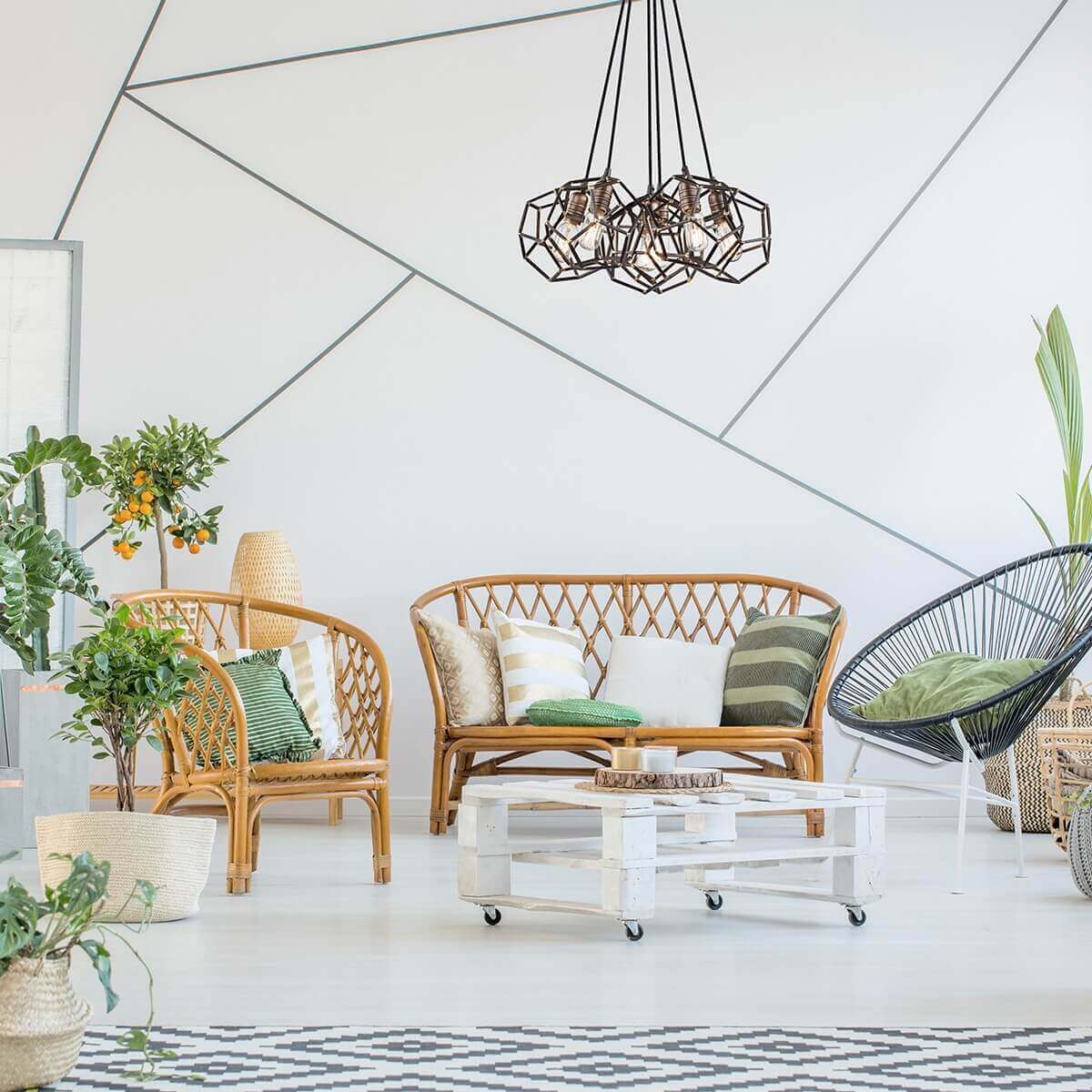 Mise en ambiance du luminaire au-dessus d'un salon bohème aux fauteuils en rotin