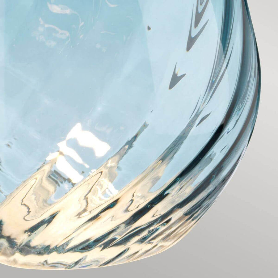 Gros plan du bas de la base en verre bleu et ses reflets texturés