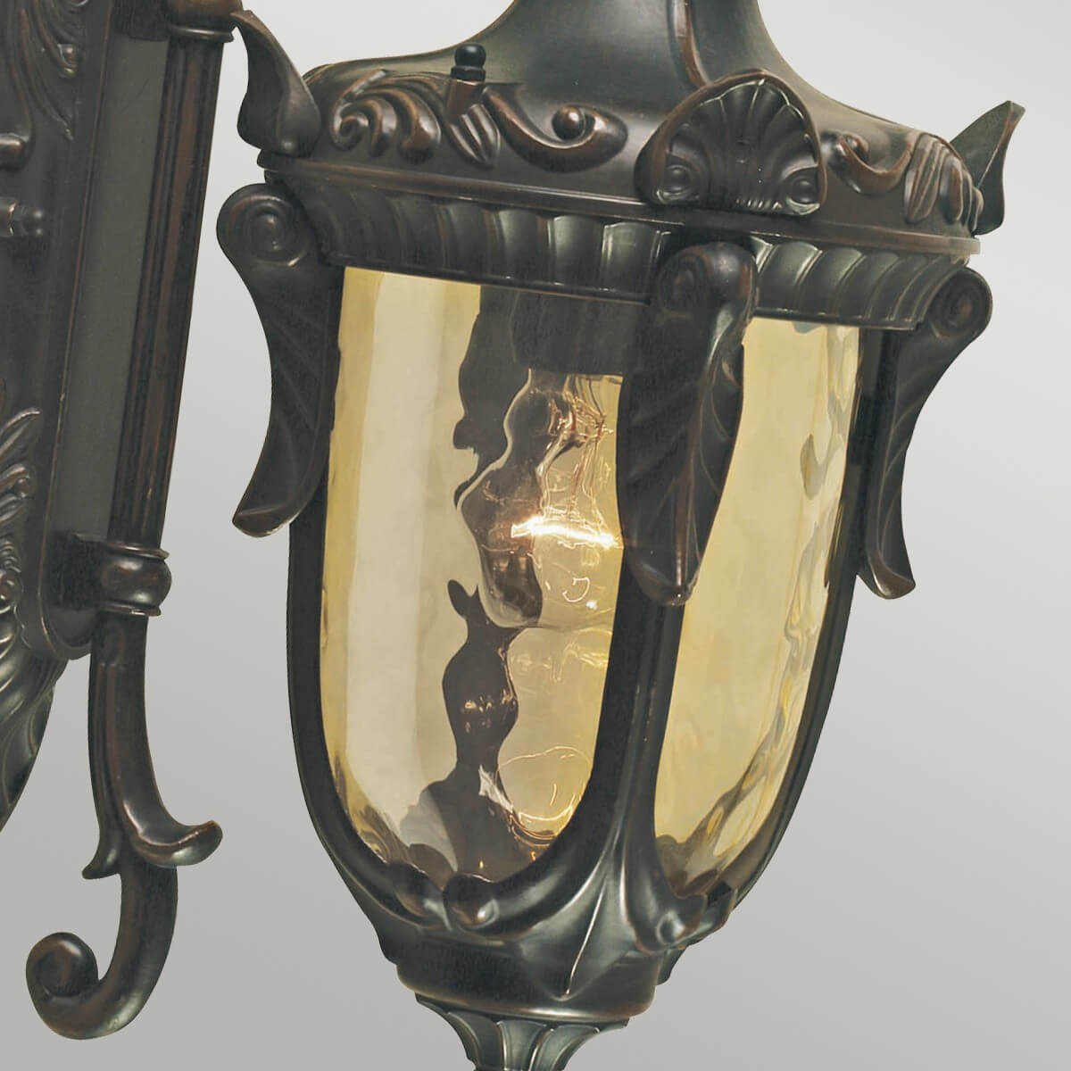 Gros plan de la lanterne, verre bombé ambré et montants décoratifs en bronze