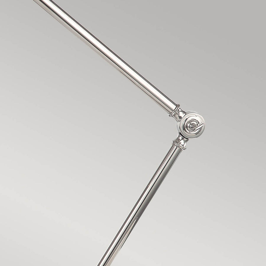 Détail de l'articulation centrale en métal chromé avec vis apparentes.