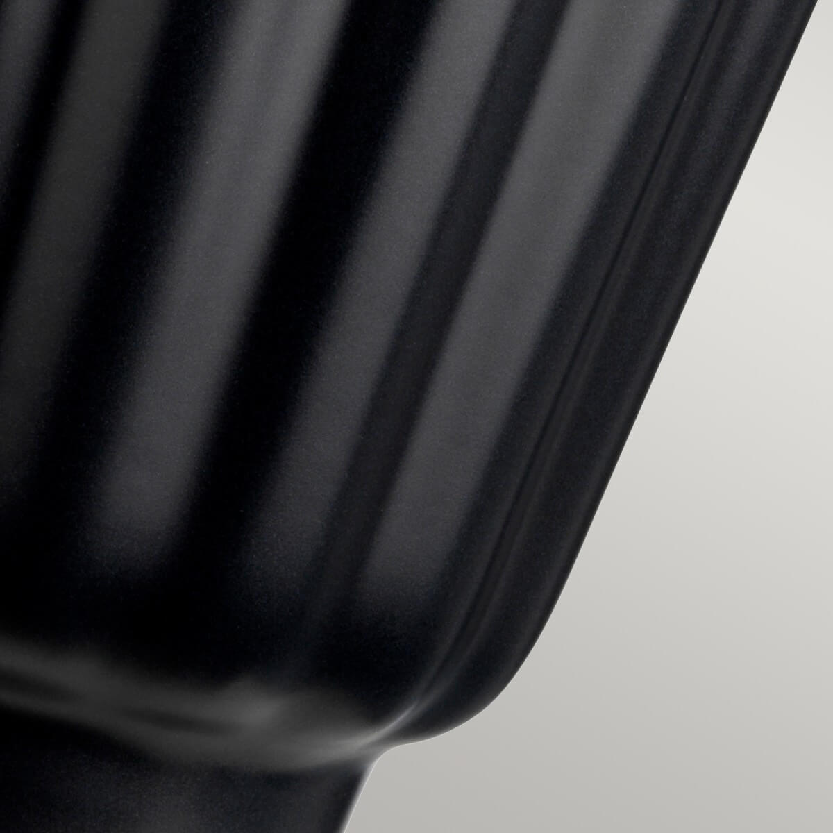 Détail de la base en céramique noire avec côtes verticales brillantes.