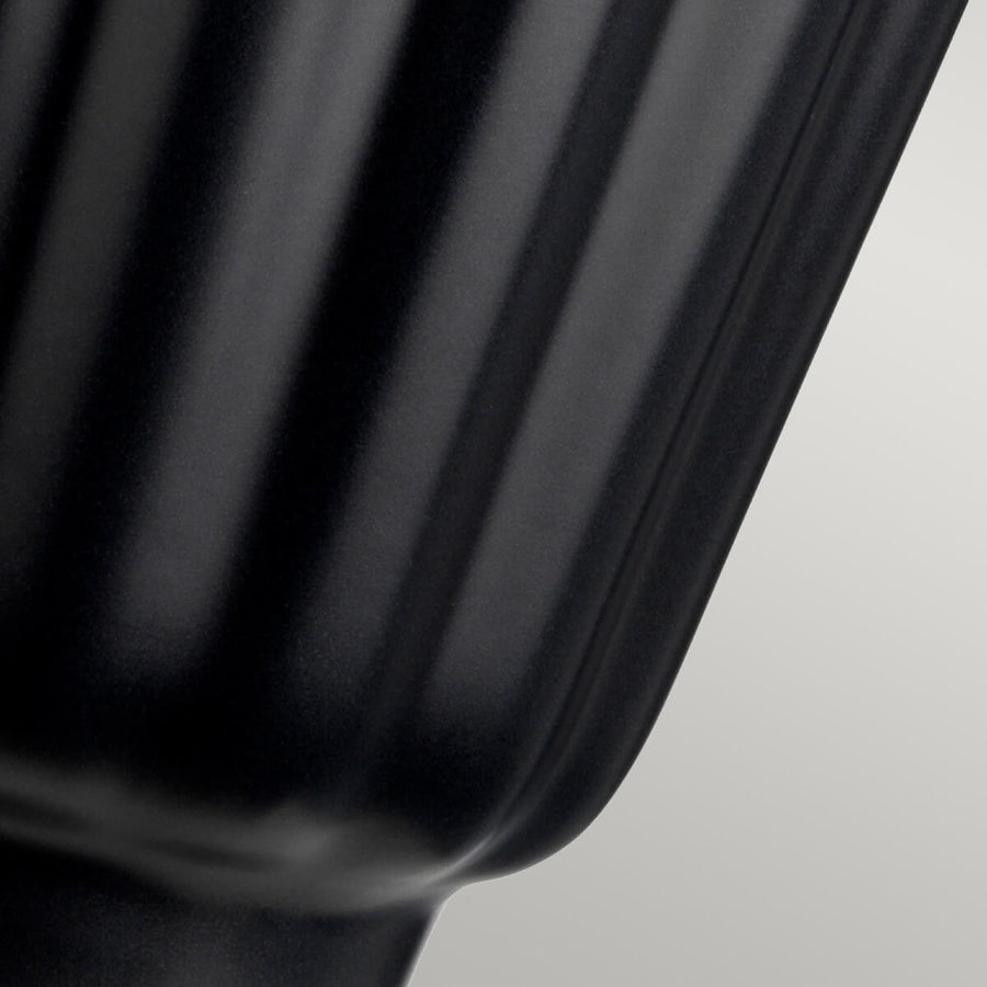 Détail de la base en céramique noire avec côtes verticales brillantes.