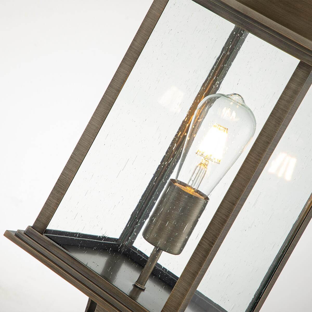 Gros plan de l'ampoule allumée derrière le verre strié, montrant la douille et le reflet.