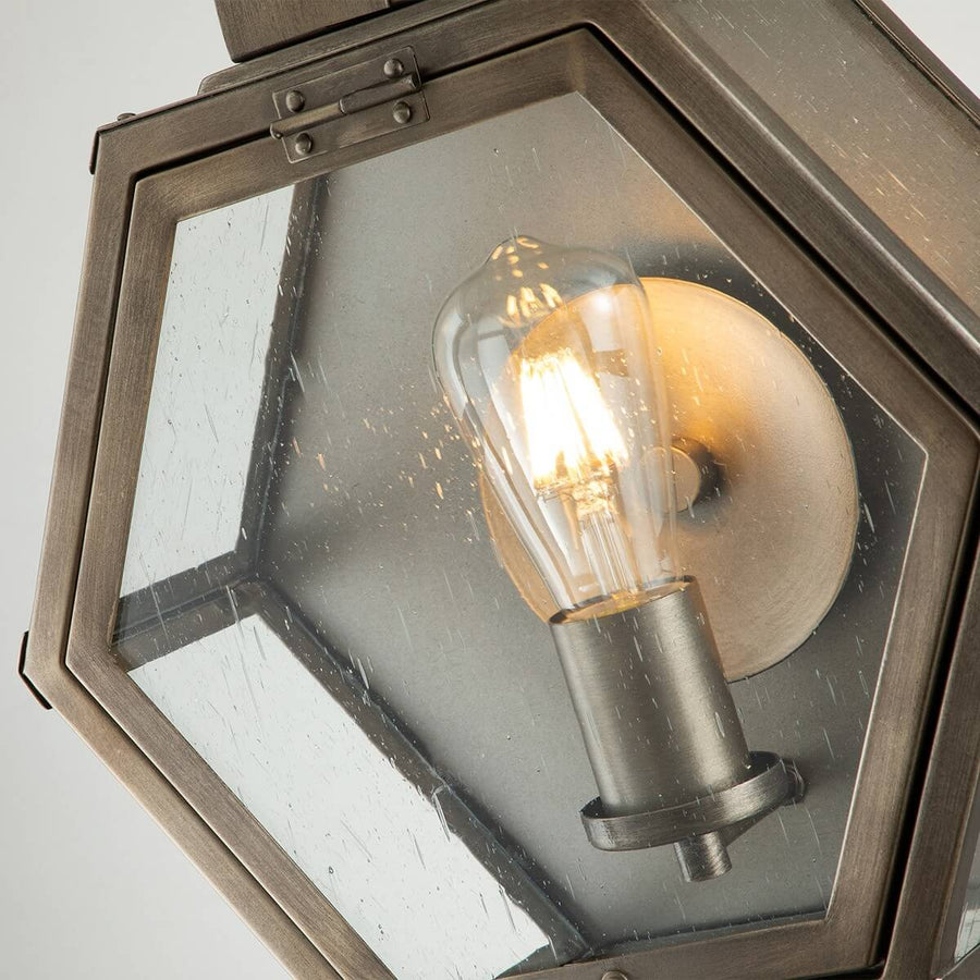 Gros plan à travers le verre grenu montrant l’ampoule à filament allumée et le support.
