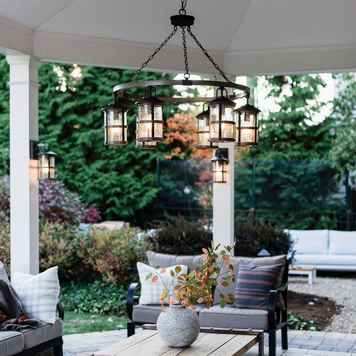 Mise en ambiance sous une terrasse couverte avec suspension et appliques allumées