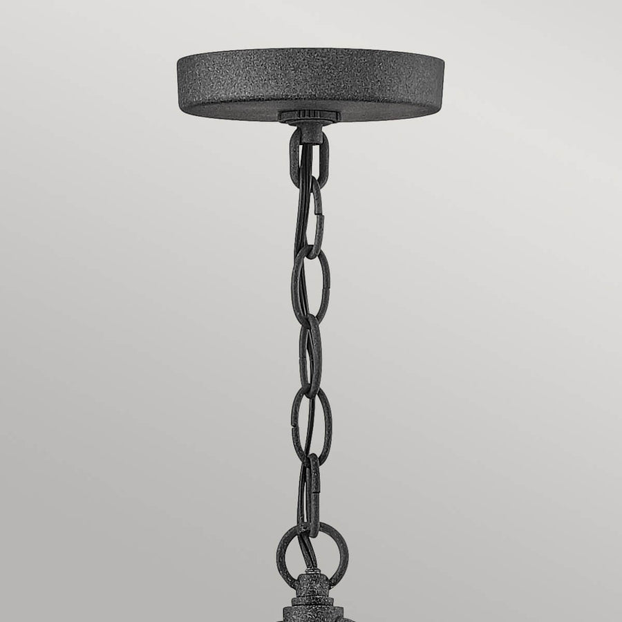 Détail du support plafond et de la chaîne métallique texturée de la suspension.