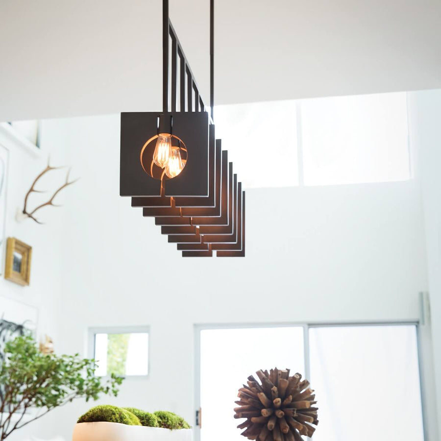 Vue en contre-plongée de la suspension allumée dans un intérieur blanc, avec bois de cerf.
