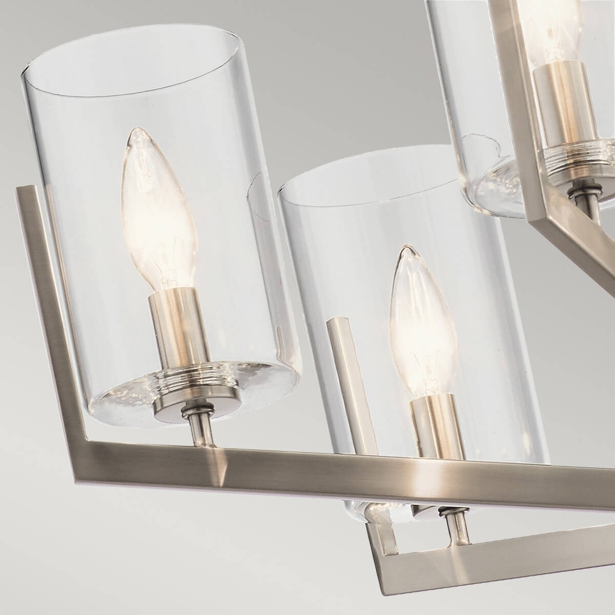 Détail de deux abat-jours cylindriques mettant en valeur la transparence du verre et les ampoules allumées.