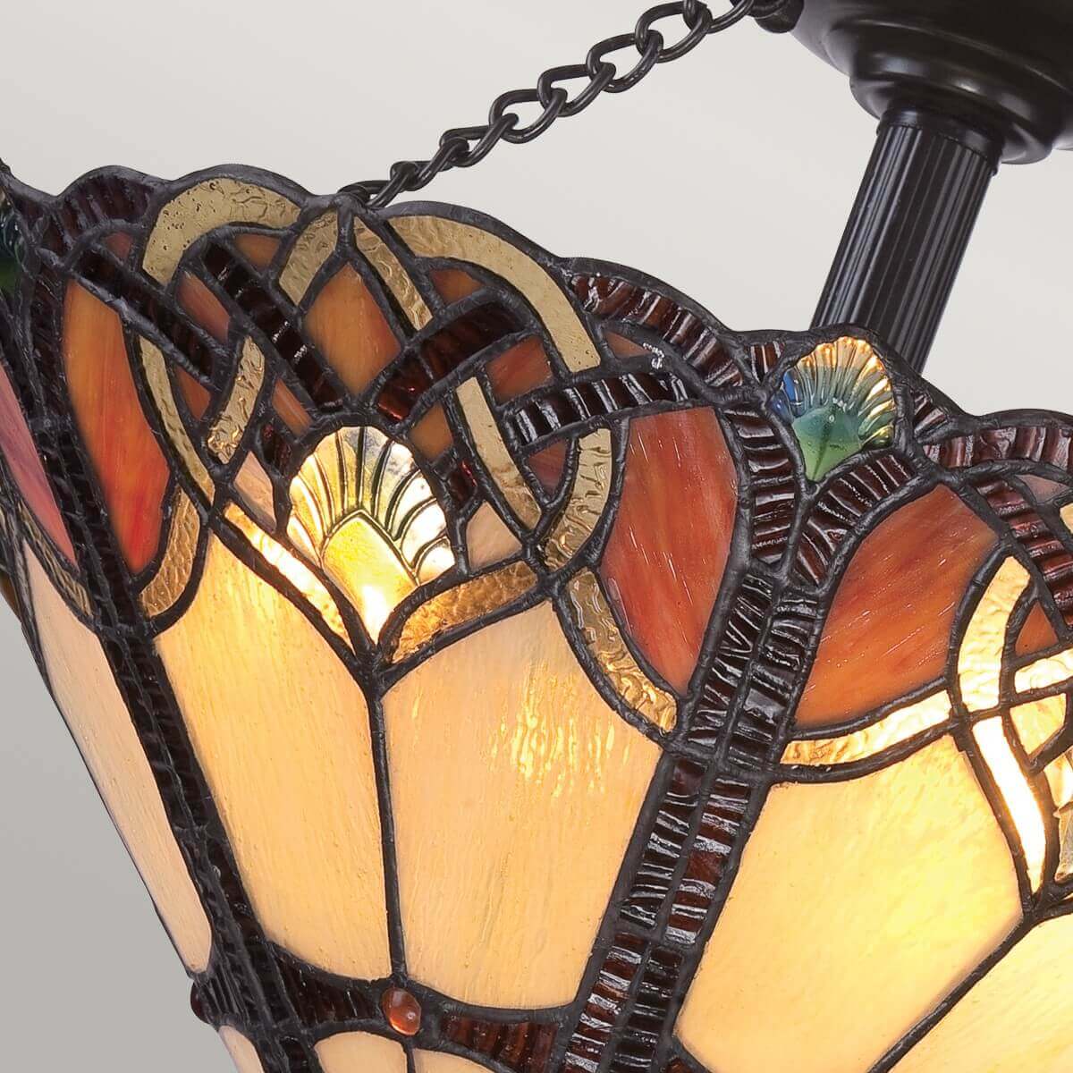Gros plan du verre tiffany miel et ambre avec cabochons verts et rouges.