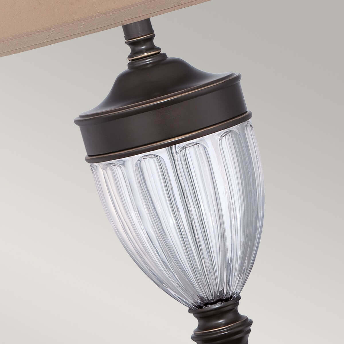 Détail du verre strié transparent et de la monture bronze de la lampe.