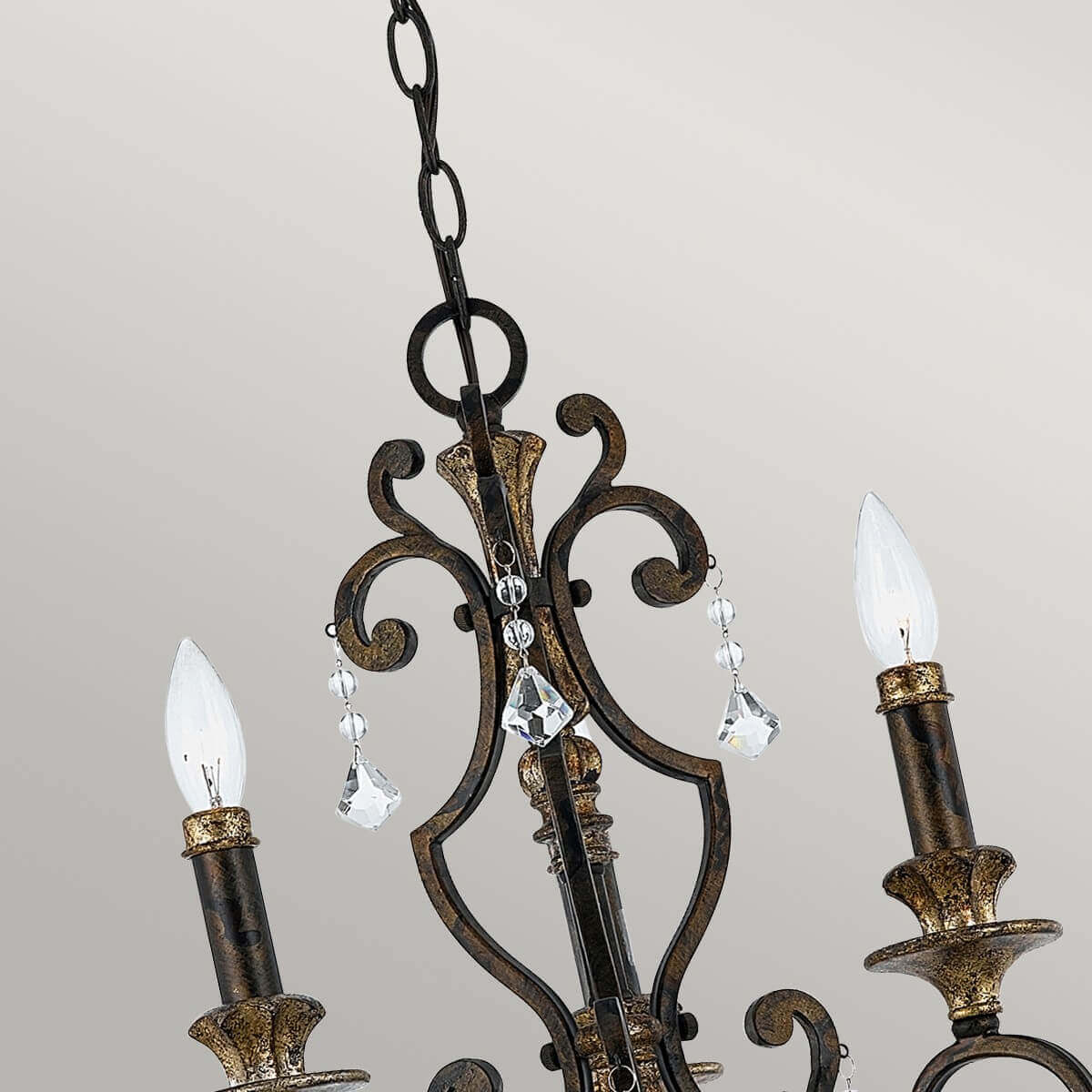Gros plan du haut du lustre : chaîne, volutes et pendeloques de cristal