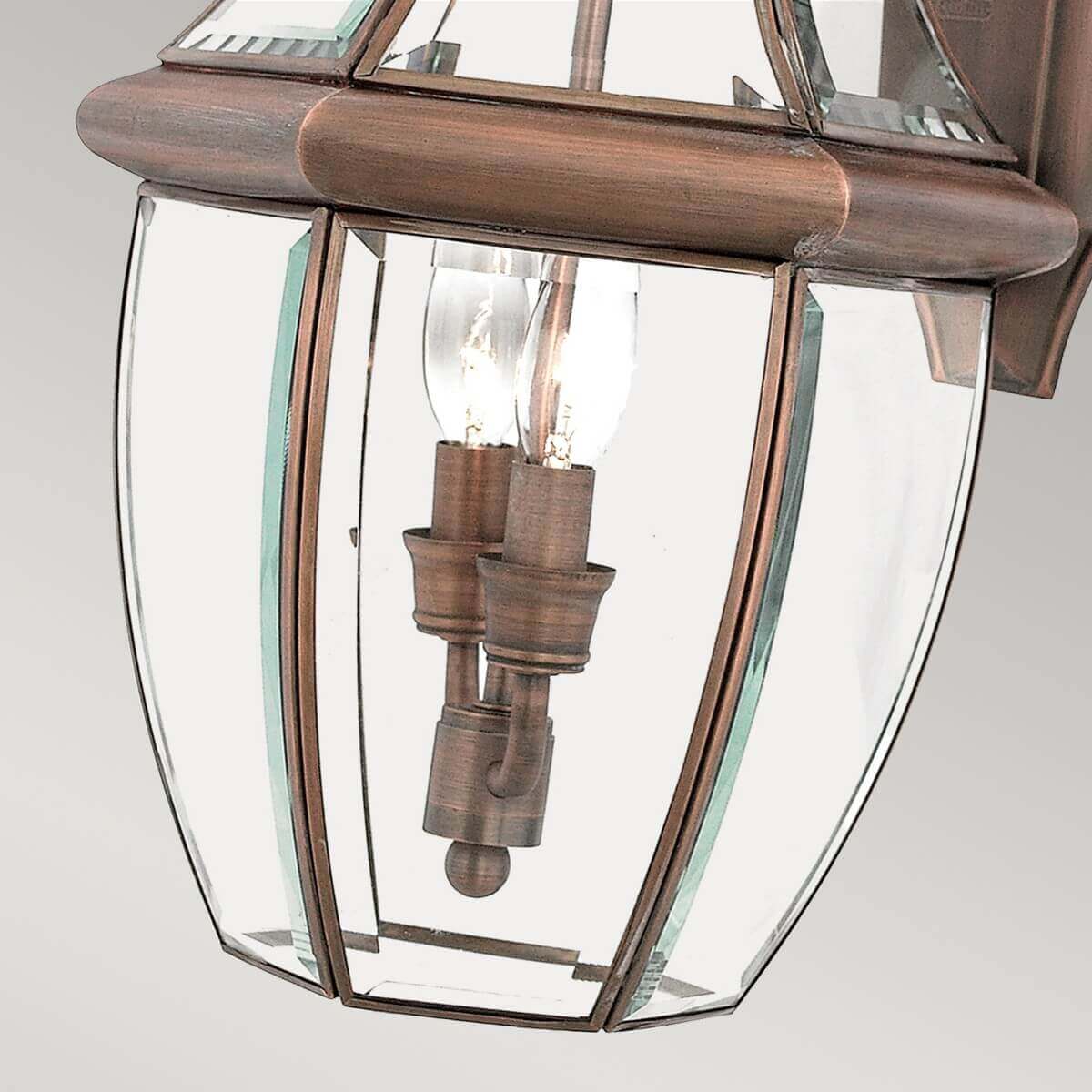 Détail du bas du luminaire montrant les ampoules, le verre clair et la structure cuivrée