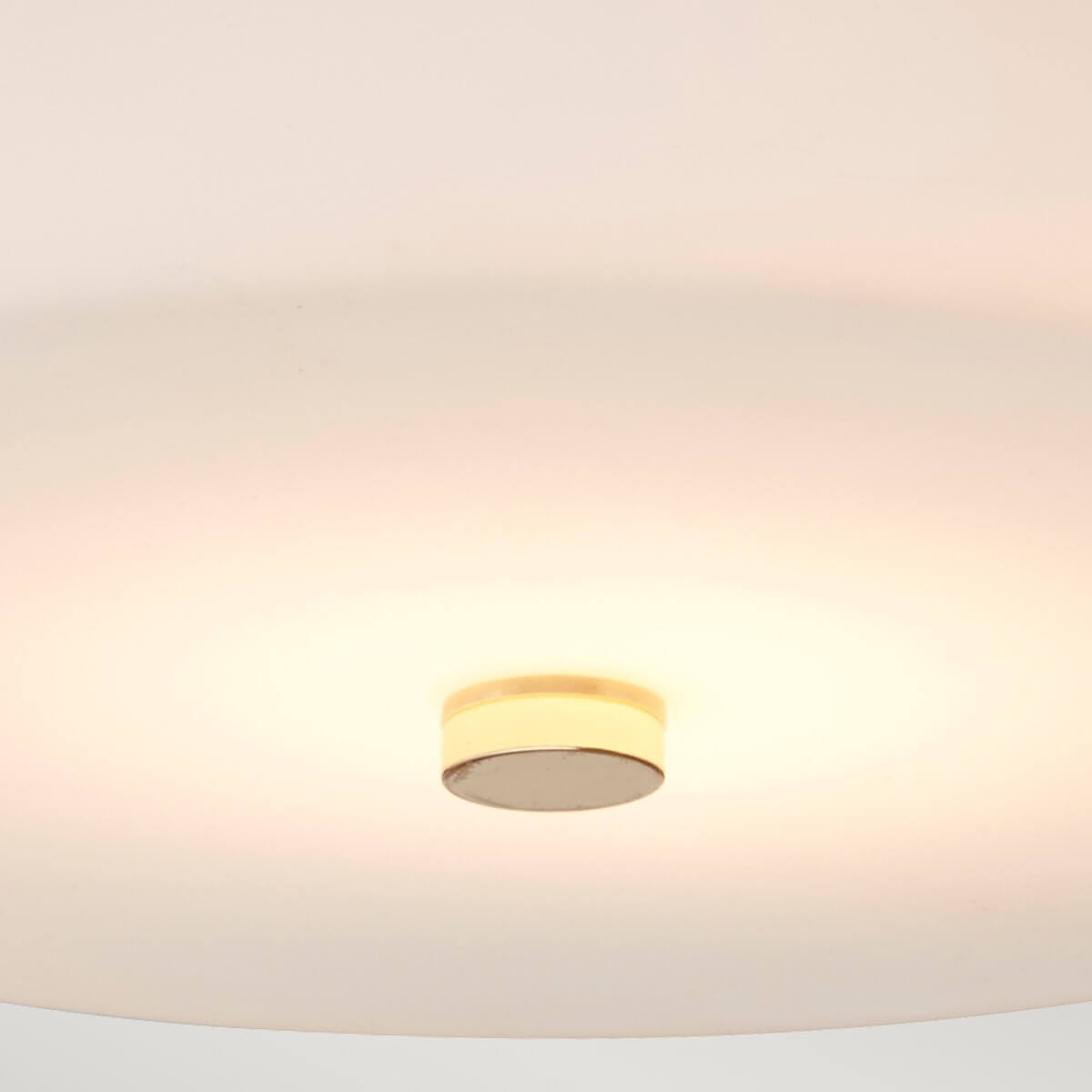 Vue par-dessous montrant le diffuseur en verre blanc et le cabochon central doré.