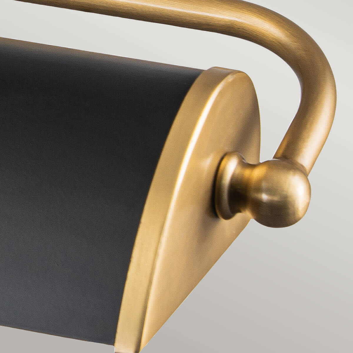 Extrémité arrondie de l'abat-jour noir avec bouton sphérique doré