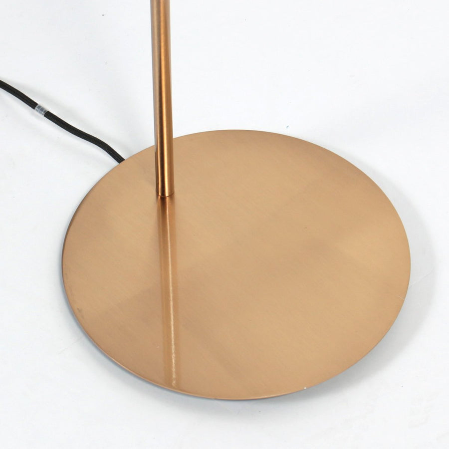 Détail de la base ronde bronze et du câble noir sortant à l’arrière.