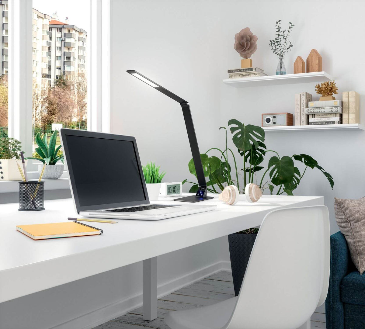 Lampe noire posée sur un bureau blanc en situation, près d'un ordinateur portable