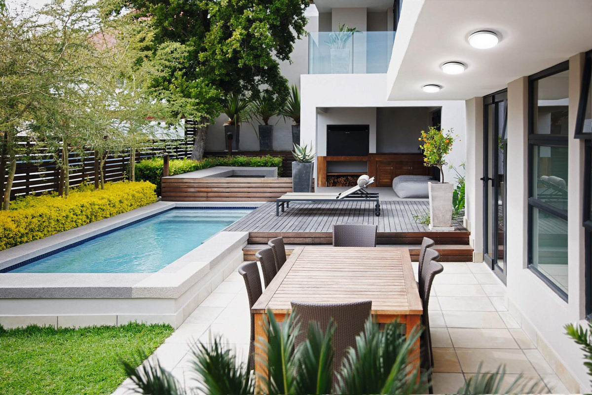 Trois plafonniers ronds éclairant une terrasse extérieure avec piscine et salon