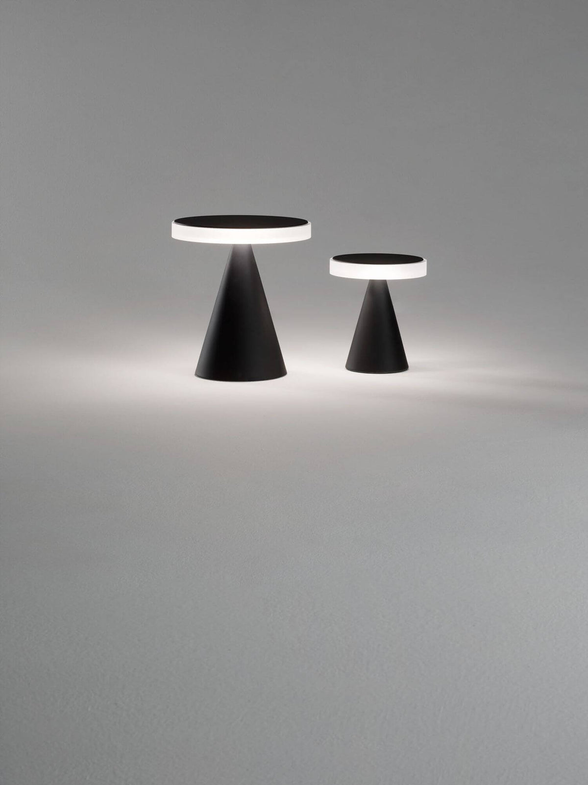 Deux lampes noires de tailles différentes côte à côte sur fond gris