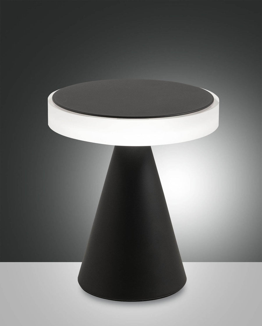 Vue de face sur fond sombre, lampe noire à abat-jour circulaire lumineux.