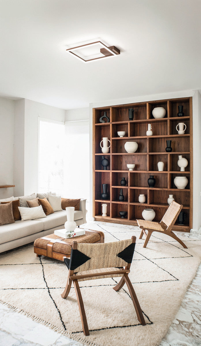 Luminaire installé au plafond d'un salon contemporain avec bibliothèque en bois et canapé beige