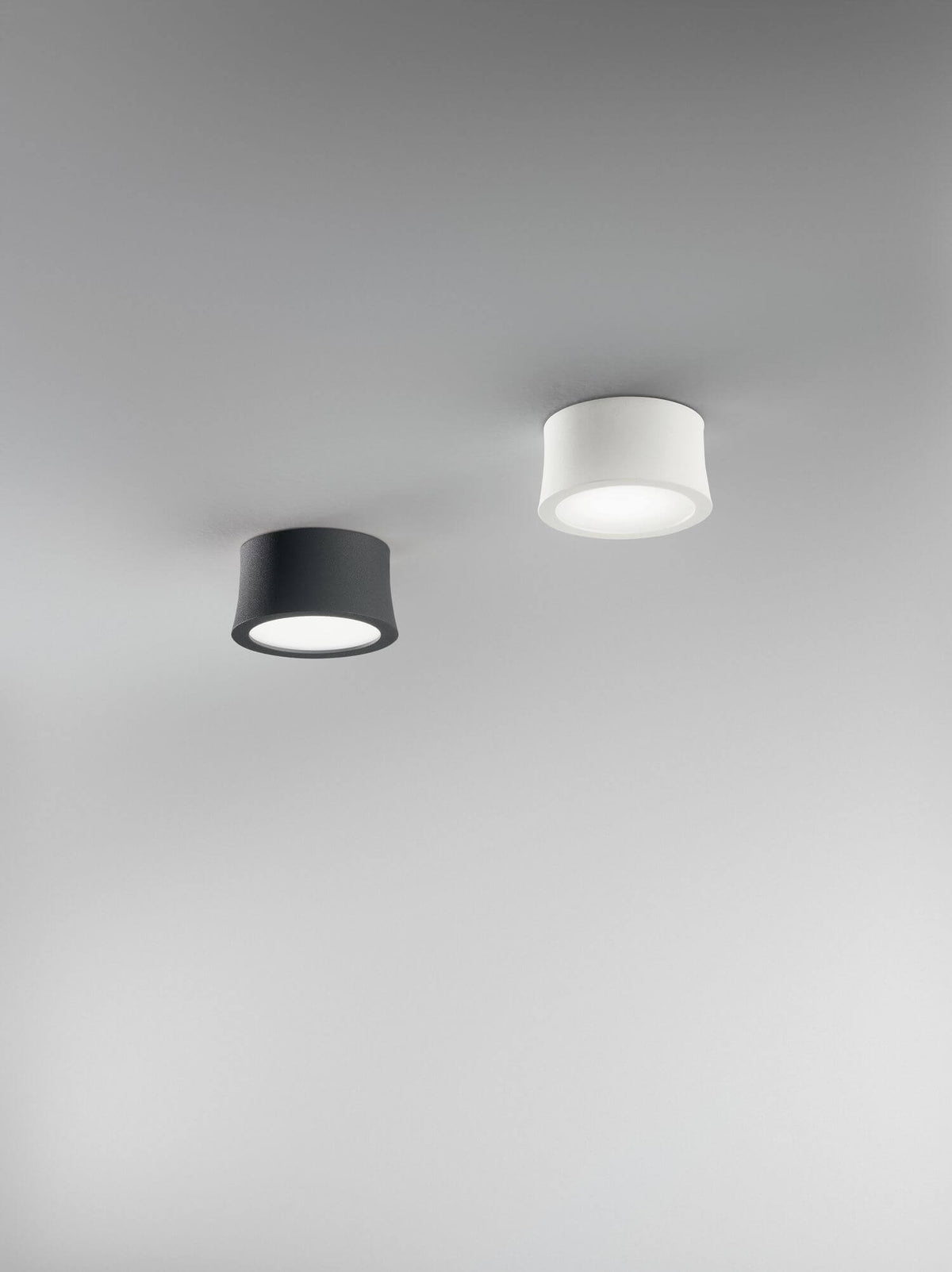 Deux spots cylindriques anthracite et blanc fixés au plafond d'une pièce claire