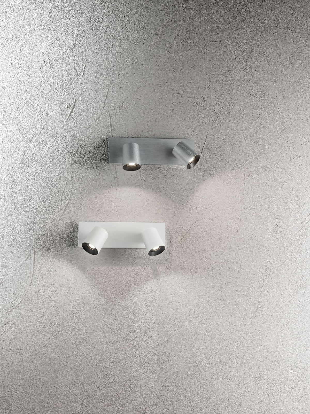Mise en ambiance au plafond, modèles blanc et aluminium brossé éclairant un mur crépi