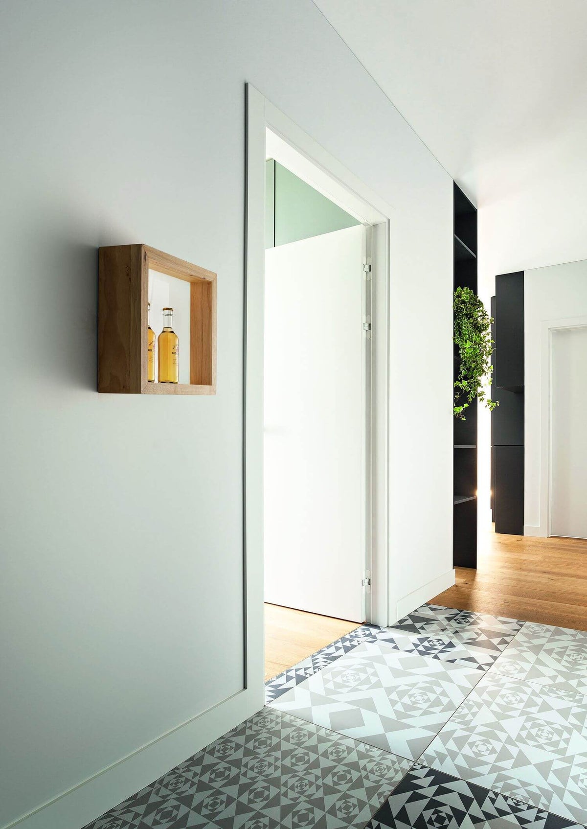 Mise en ambiance : applique en bois dans un couloir au sol carrelé géométrique