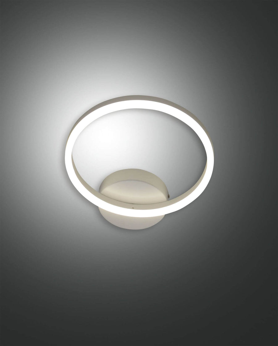 Applique murale blanche de face avec anneau LED lumineux et socle ovale central.