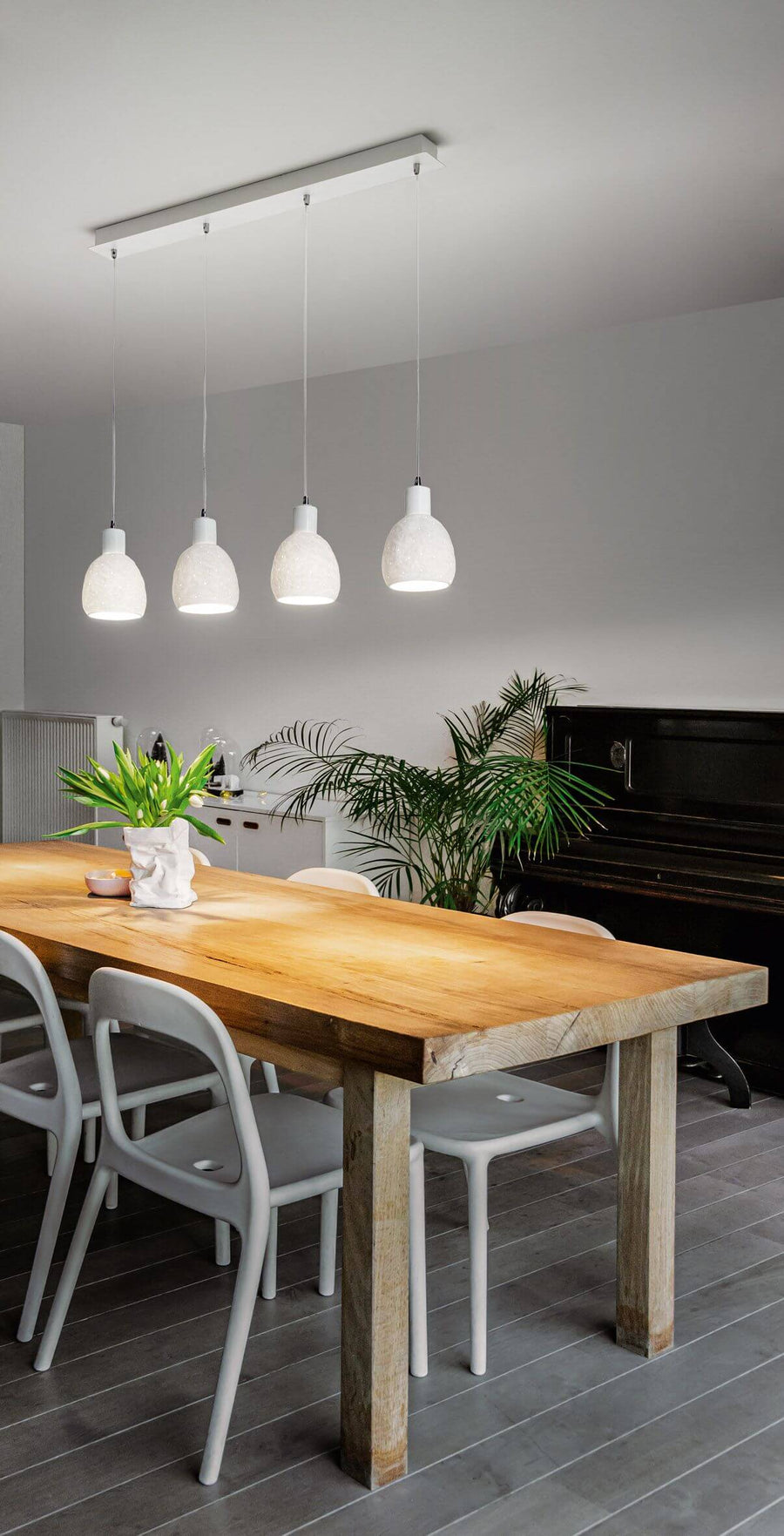 Vue en situation au-dessus d'une table en bois, suspension allumée dans une salle à manger