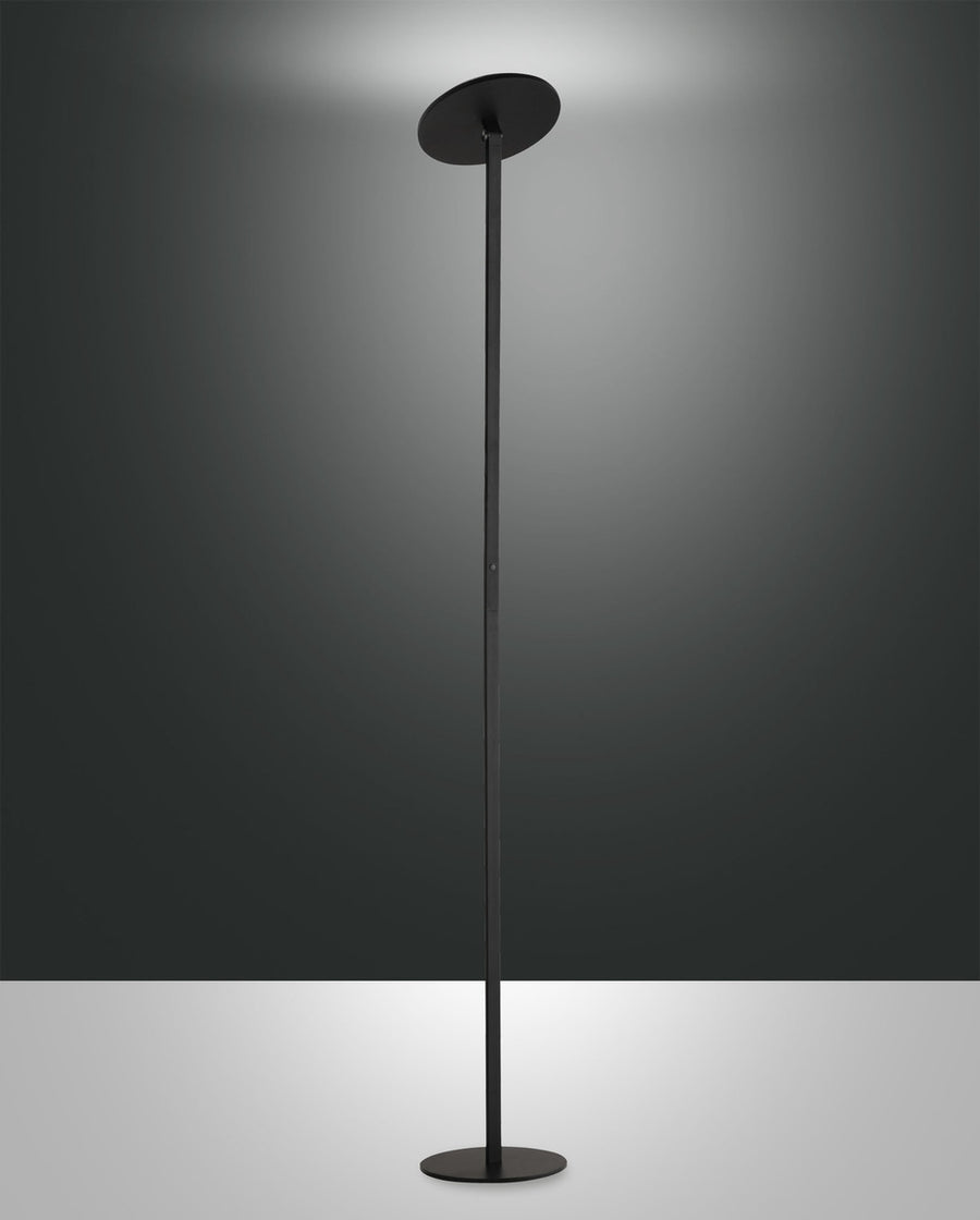 Lampadaire noir de face sur fond gris, tige fine et disque diffuseur orienté vers le haut